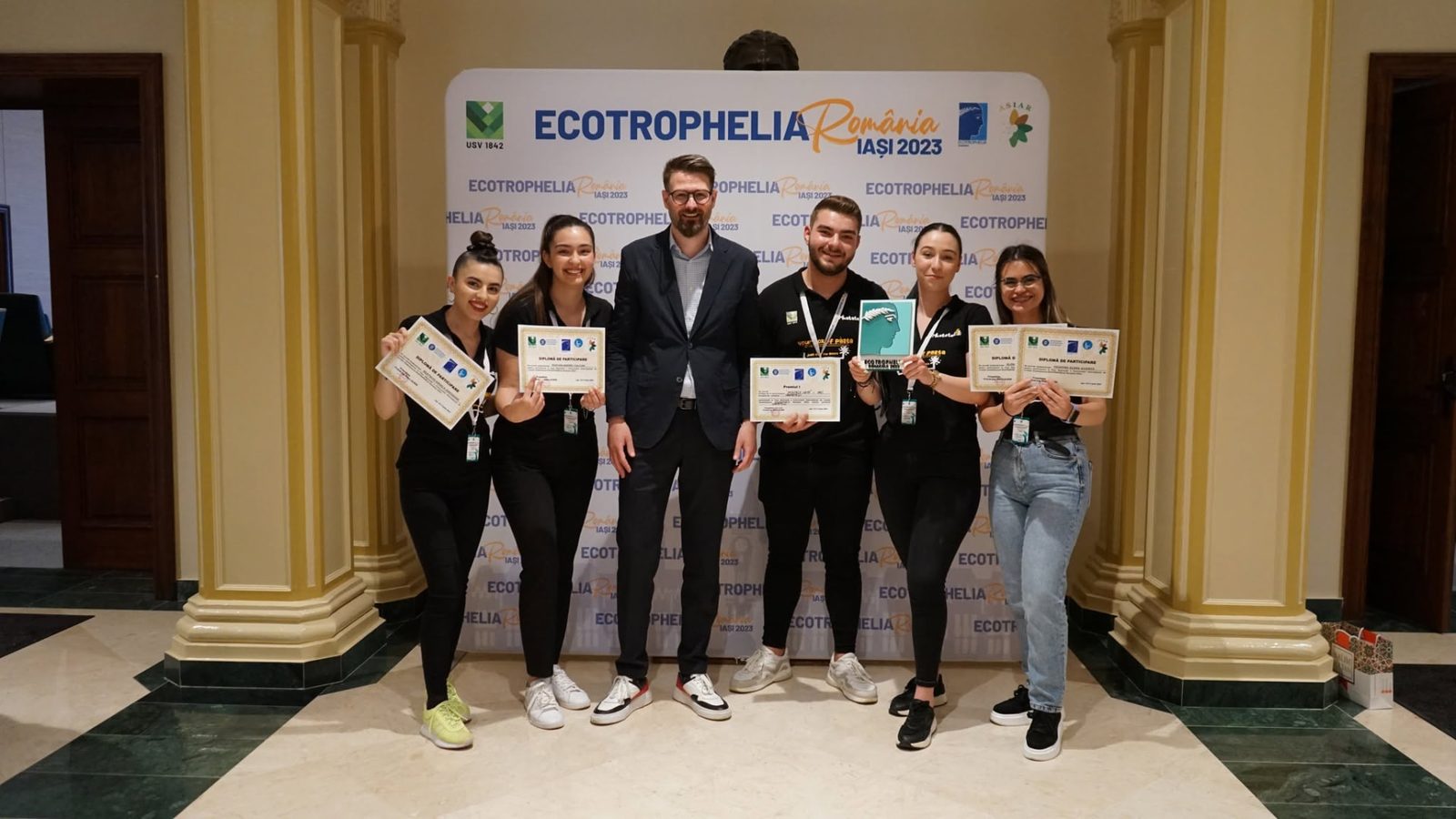 Echipă cu diplome și trofeul ediției, în fața panoului oficial