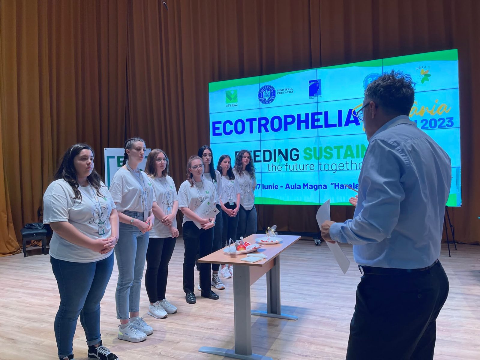 Echipă de studente pe scenă, în fața ecranului oficial al ediției de la Iași