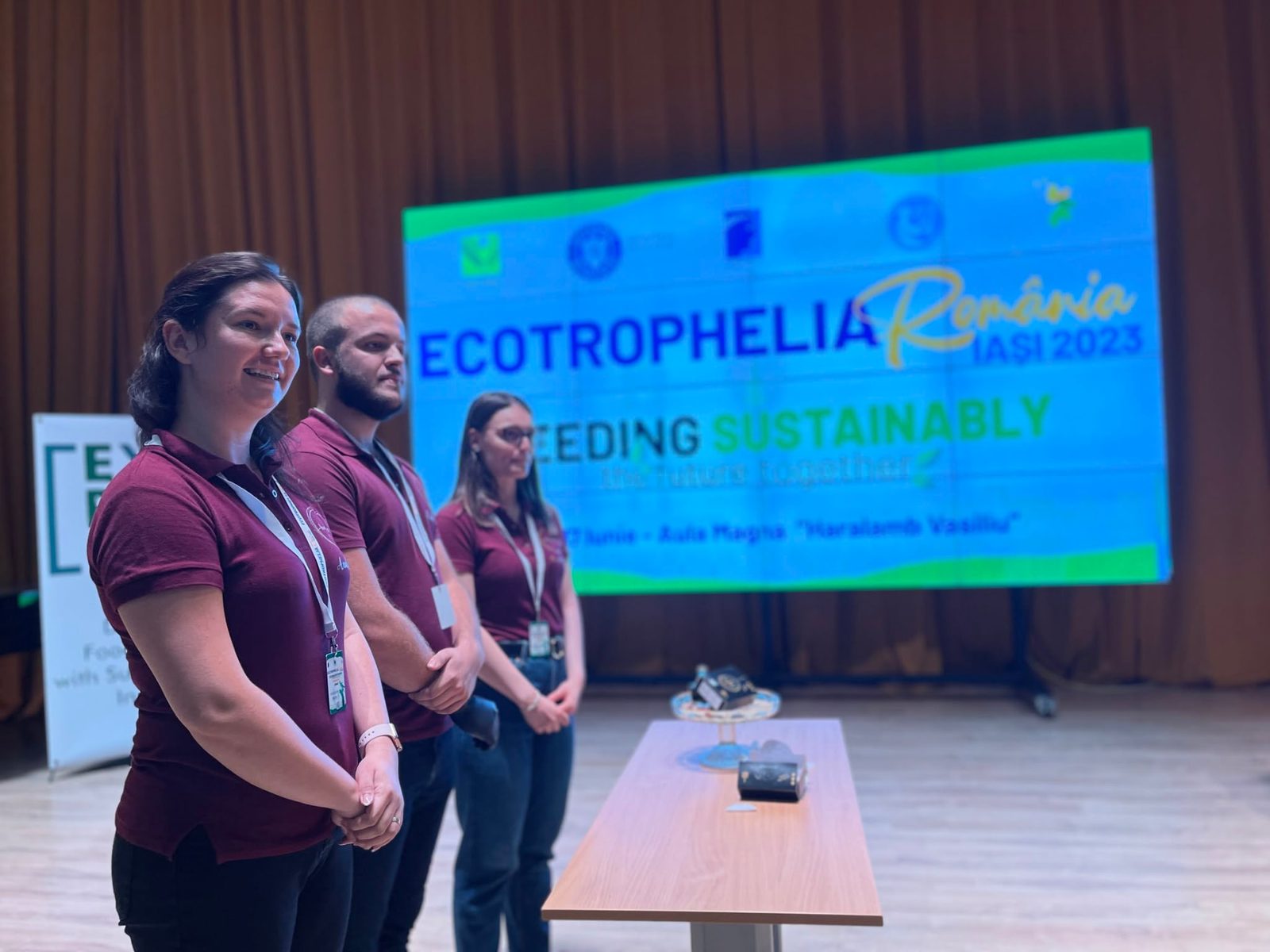 Echipă de studenți își prezintă produsul pe scenă, în fața ecranului ECOTROPHELIA România Iași 2023