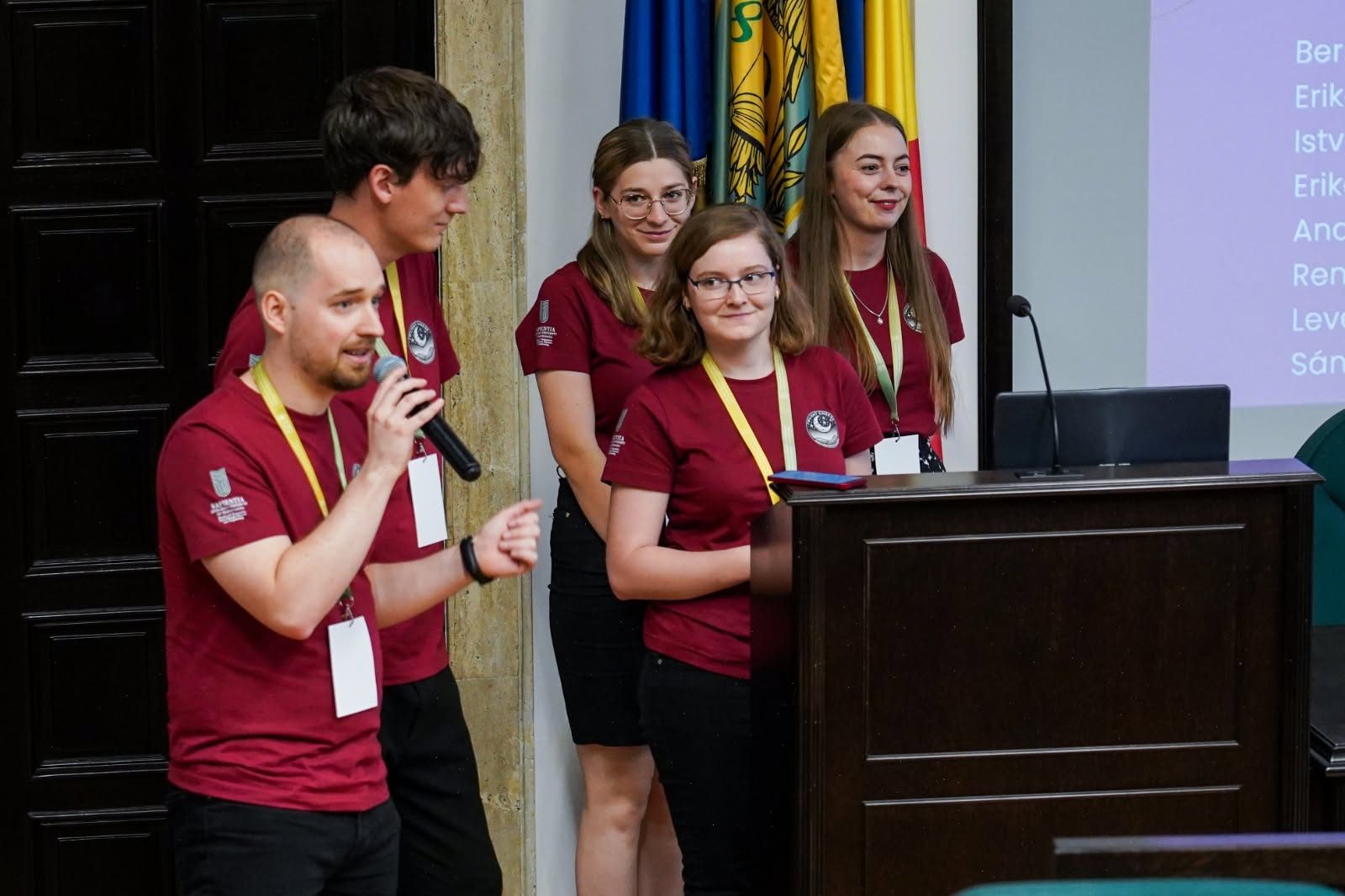 Echipă de studenți susținând prezentarea la pupitrul din aulă